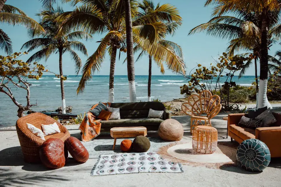 Beach lounge with layered rugs, poufs and low seating between palms