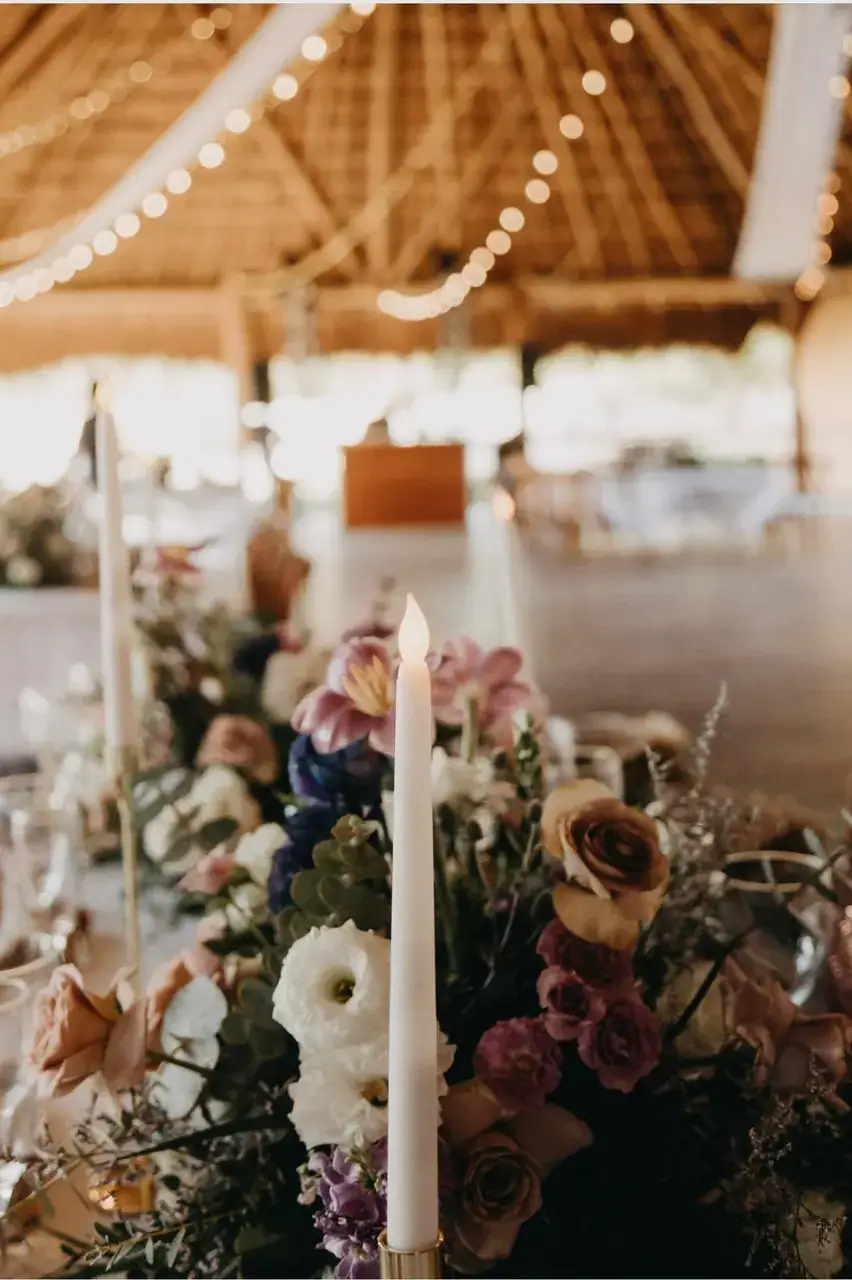 Close view of taper candles among blush and burgundy florals