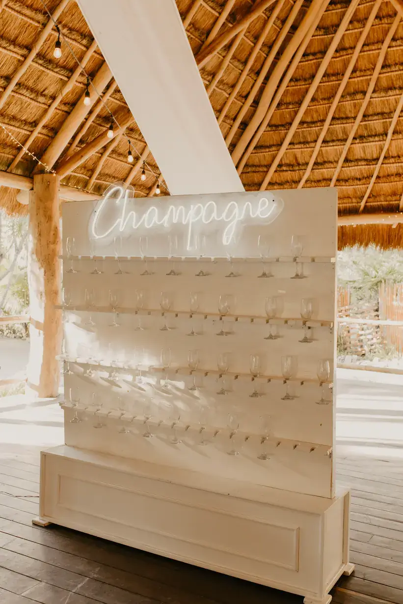 Champagne wall with neon signage under a palapa roof
