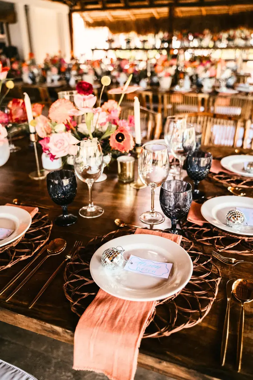 Long table set with coral florals, blush runner and copper chargers
