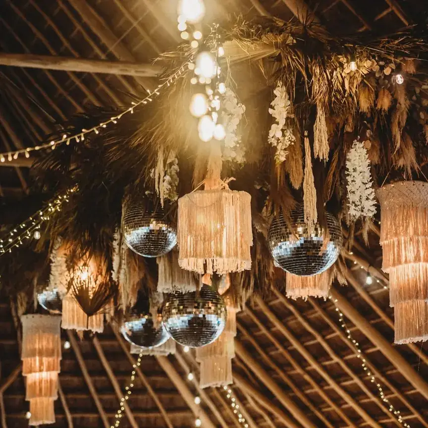 Fringed chandeliers and mirror balls glowing over a reception at night