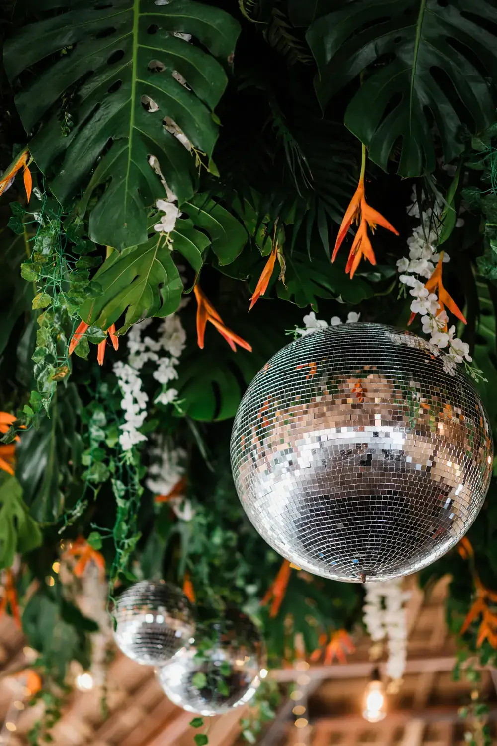 Mirror ball suspended among monstera leaves and tropical greenery