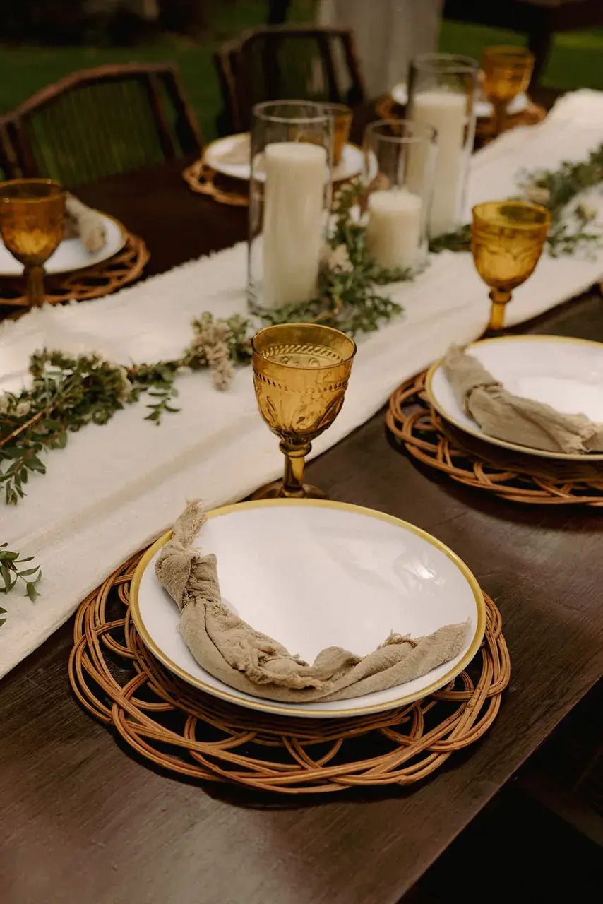 Table dressed with green goblets, woven chargers and a pale runner