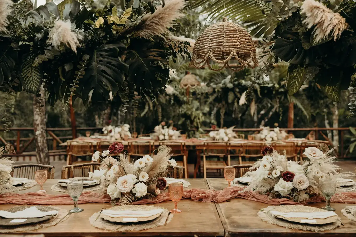 Long banquet table beneath hanging greenery and white florals
