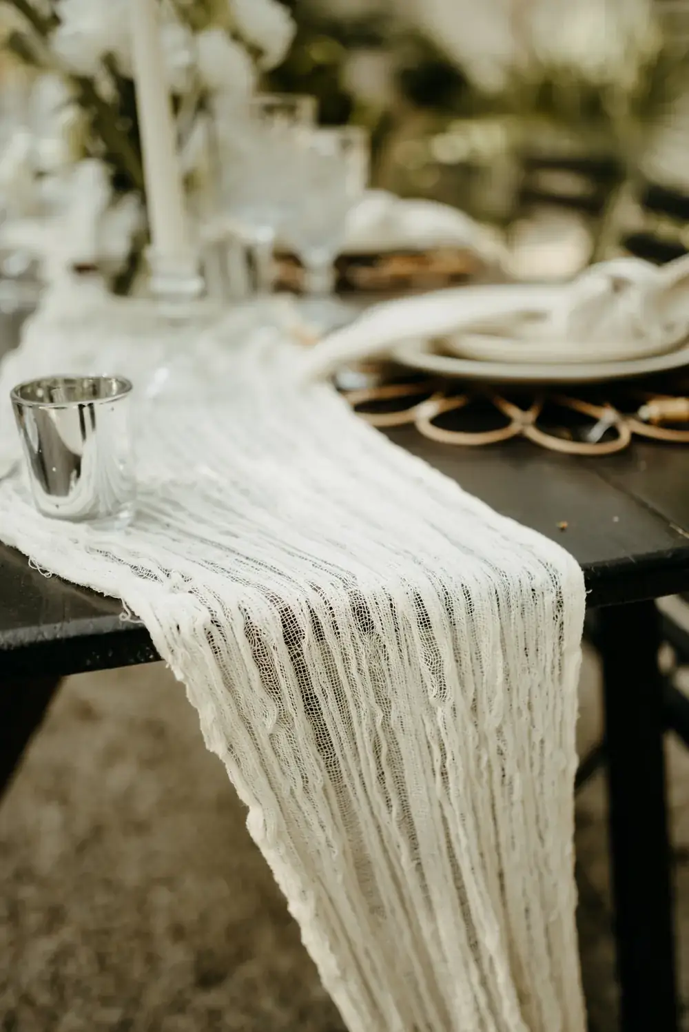 Long table dressed with a macrame runner, woven chargers and low florals