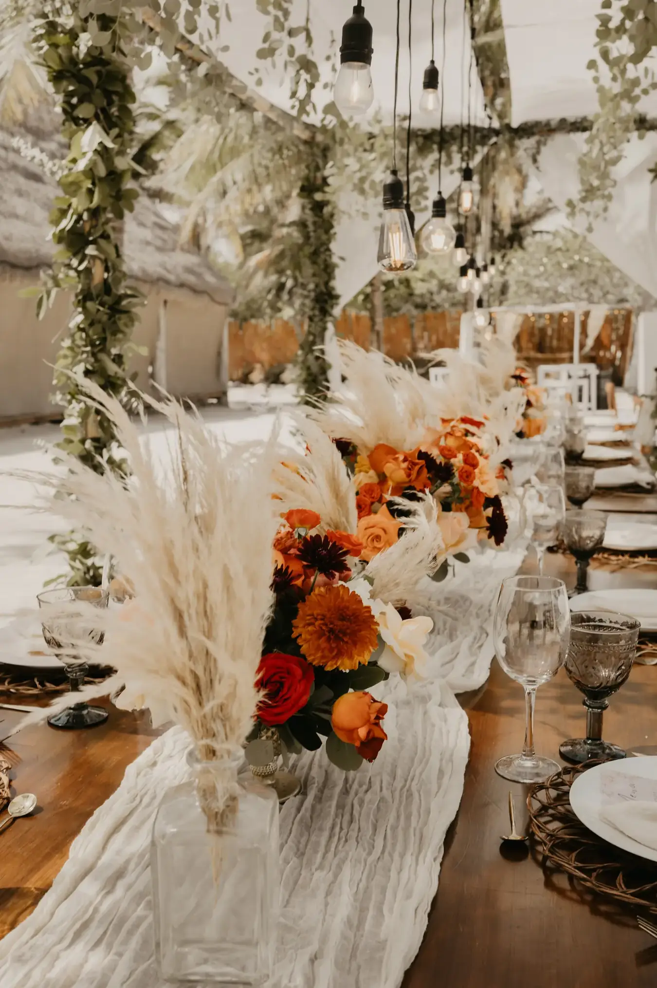 Tablescape with orange florals, pampas grass and a white gauze runner