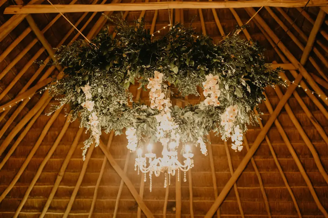 Palapa ceiling hung with greenery and cascading white florals