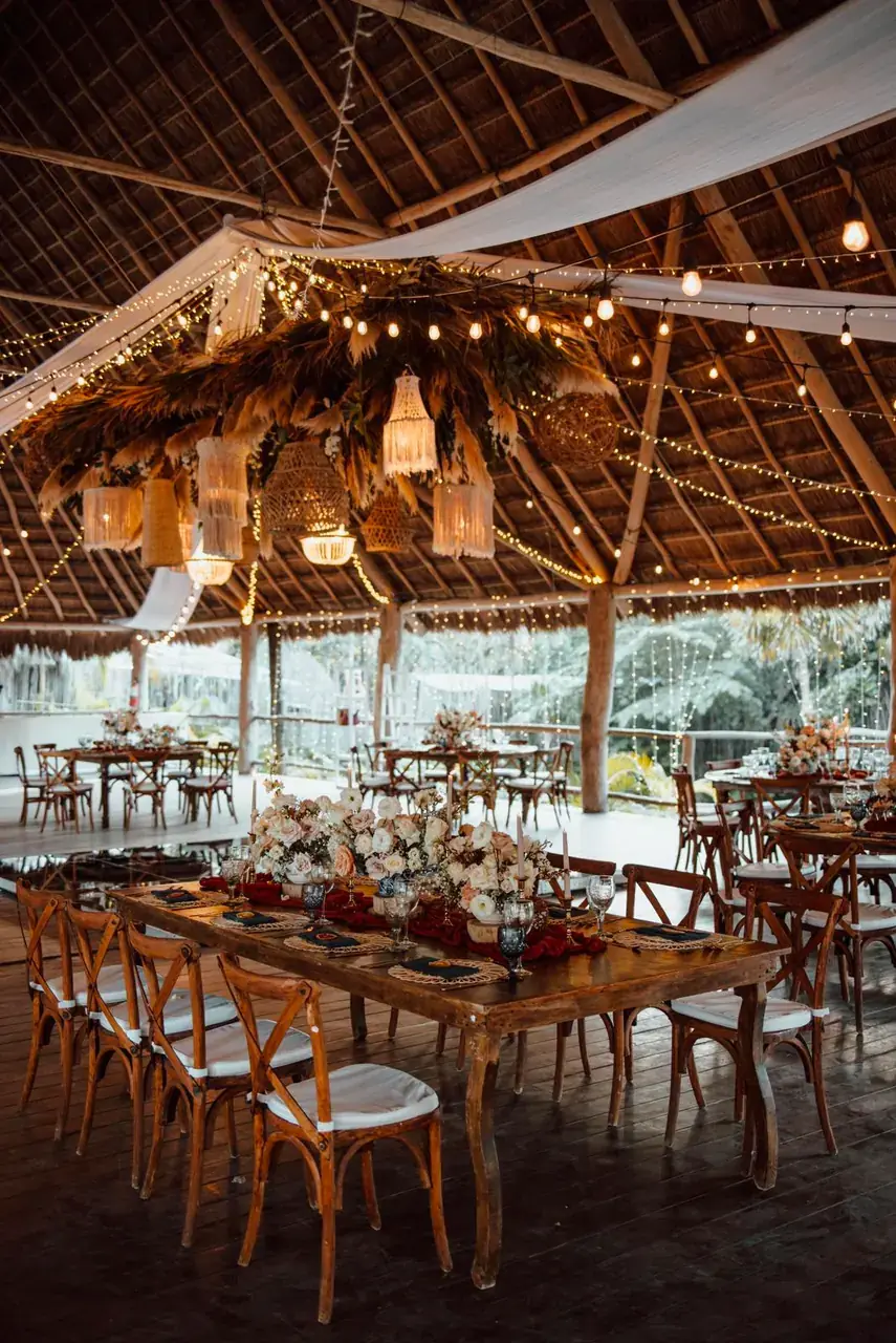 Palapa reception with long tables and deep red florals