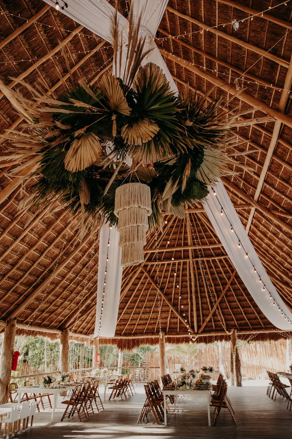 Suspended pampas and dried palm chandelier under a palapa roof