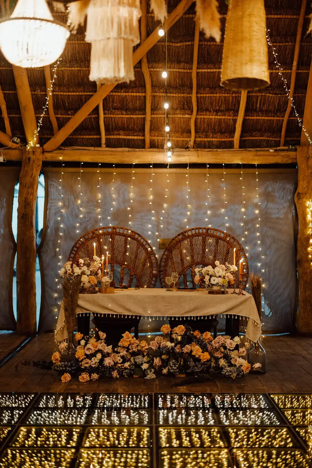 Sweetheart table with peacock chairs, orange florals and a gold backdrop