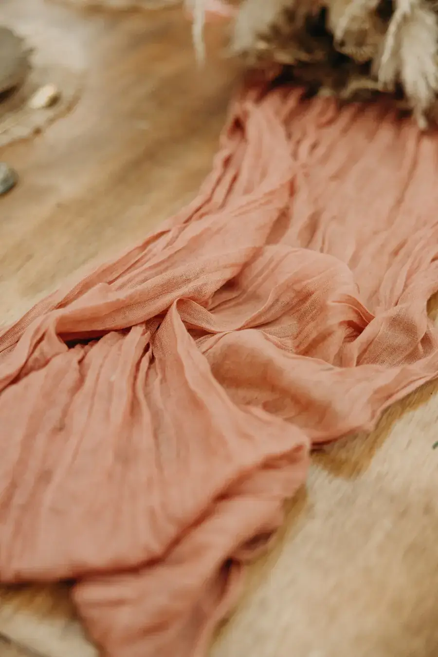 Close detail of hand-dyed blush cheesecloth folded across a table