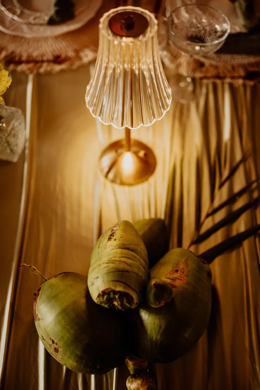 Overhead view of green coconuts and a small crystal lamp on gathered olive fabric