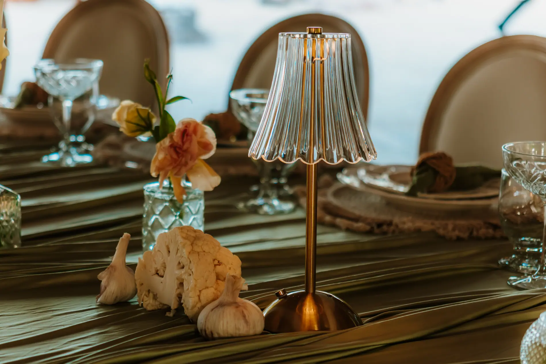 Ikebana-inspired wedding tablescape with cauliflower, garlic and a single rose beside a small crystal lamp