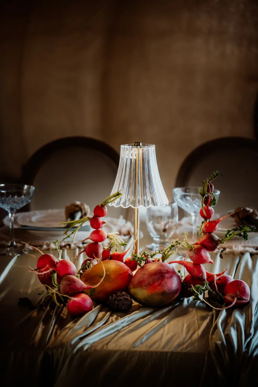 Radishes and mango arranged as a sculptural centerpiece on olive draping