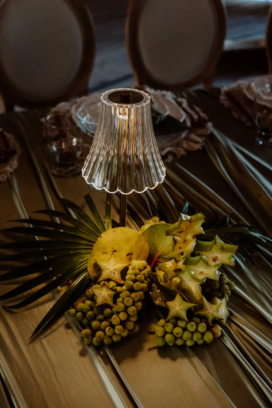 Starfruit, sea grapes and a palm fan arranged under a small crystal table lamp